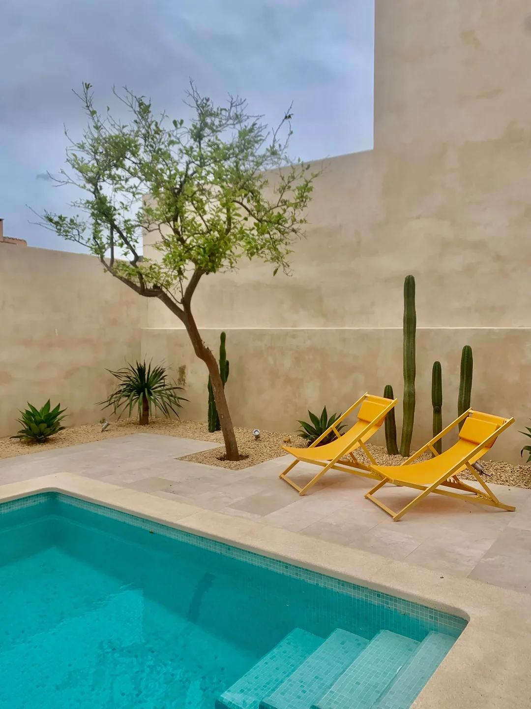 BINISSALEM COURTYARD POOL TERRACE WITH YELLOW LOUNGERS AND SCULPTURAL SPECIES SESTEPA DESIGN