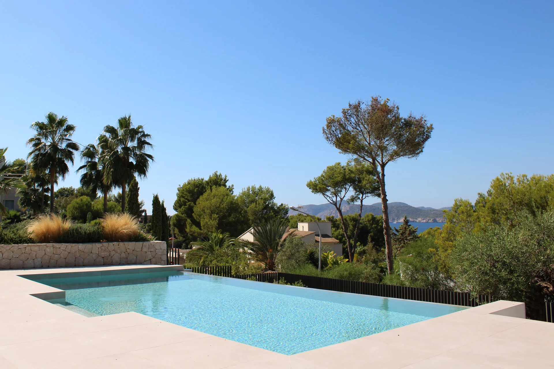Piscina infinita turquesa con vistas al mar Mediterráneo y las colinas de pinos en Santa Ponsa, Mallorca - S'Estepa Design