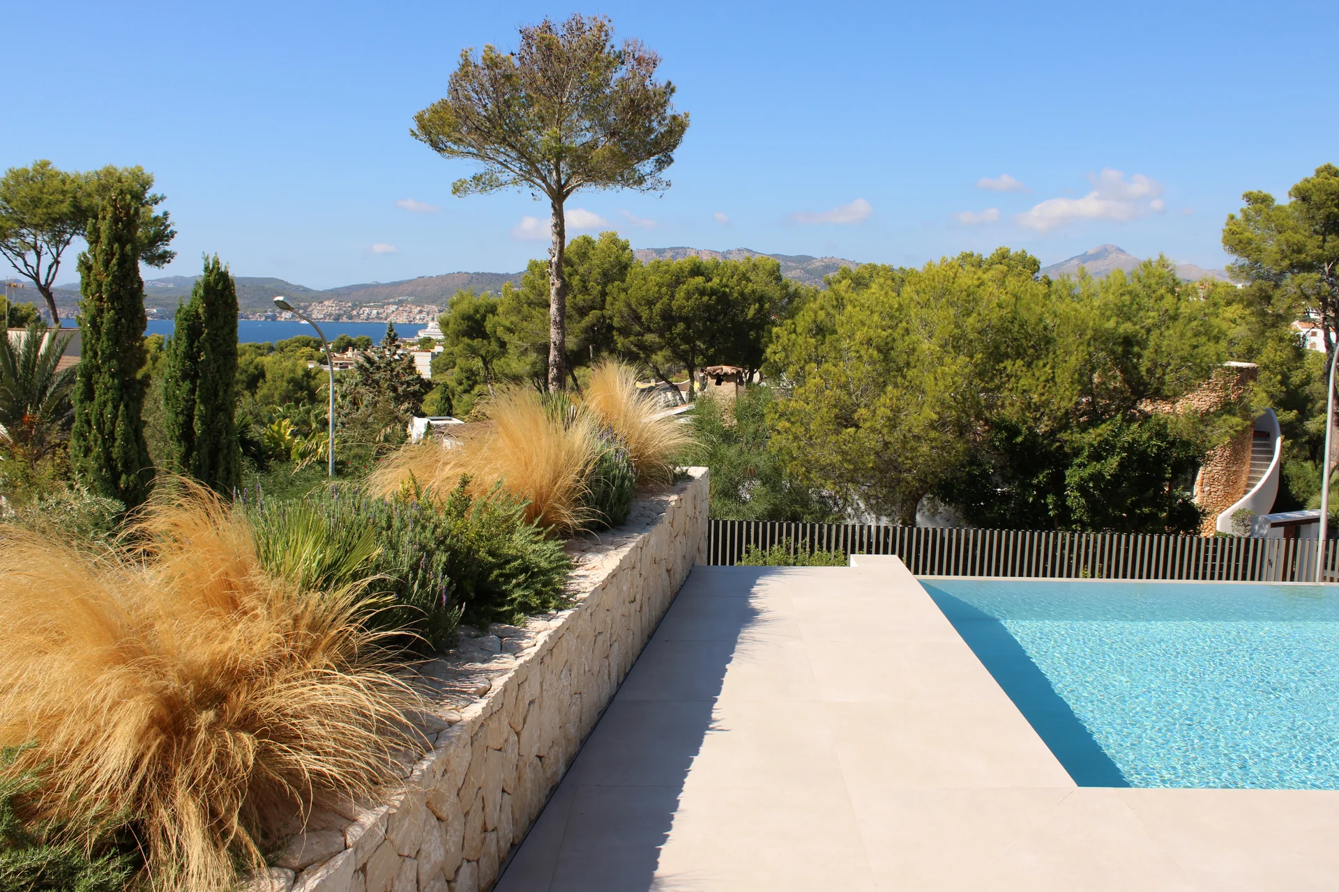 Jardinera de piedra con Stipa junto a la piscina con vistas panorámicas al mar y la montaña - S'Estepa Design